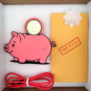 Griftmeter Piggy Bank shell in its shipping box with the dial lit and showing a live reading, beside the envelope, stand and red cable
